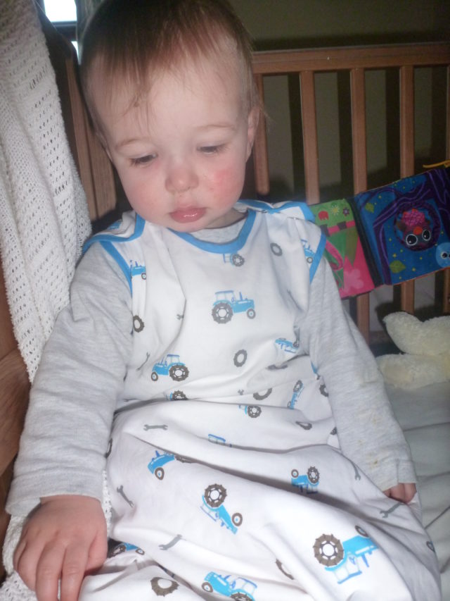 toddler waking up from sleep in a tractor grobag