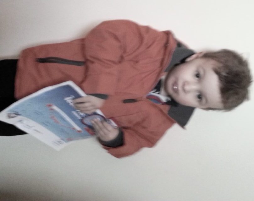 Boy in coat with ASA stage 1 swimming certificate