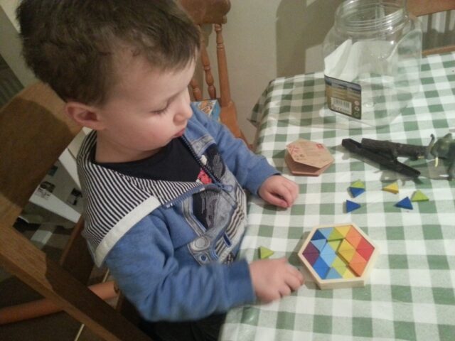 toddler playing a colour geomix triangle puzzle