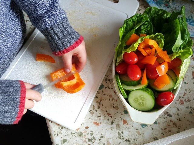 little boy chopping veg for a salad