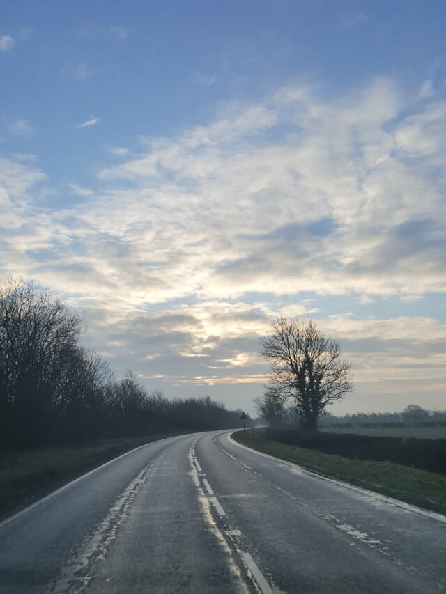 road leading into the distance and blue cloudy skies