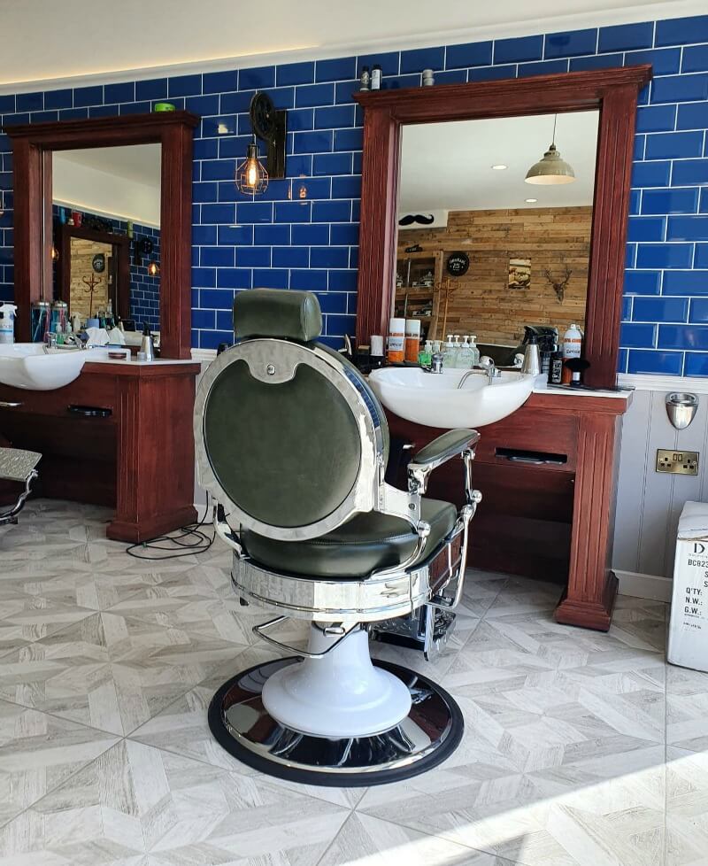 barber's chair in front of mirrors and blue tiles