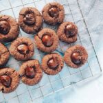 chocolate orange thumbprint cookies on wire rack blue background