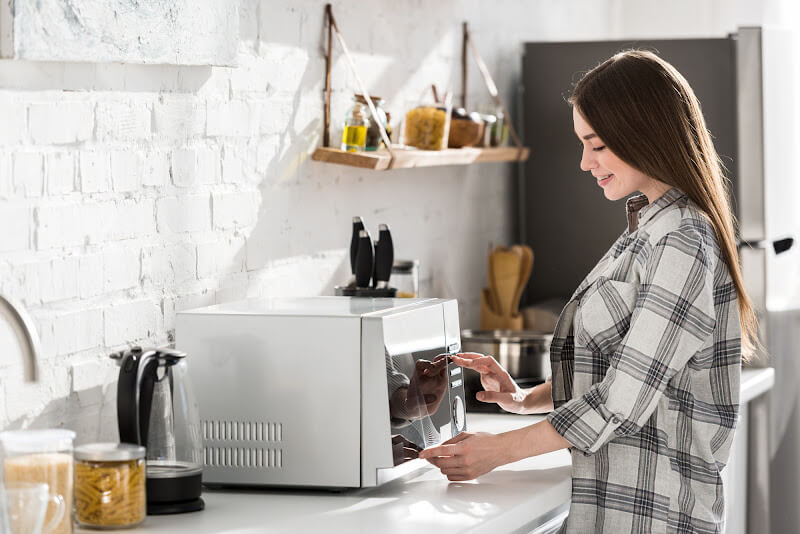 woman using microwave in the kitchen