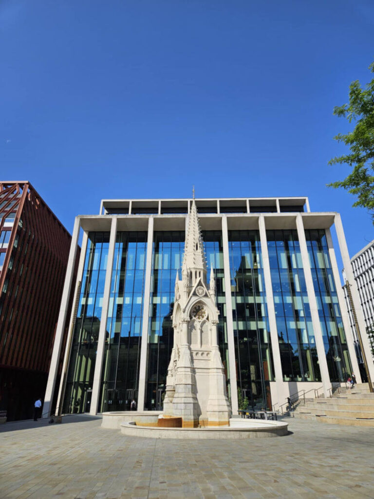 Spire statue in front of modern glass building